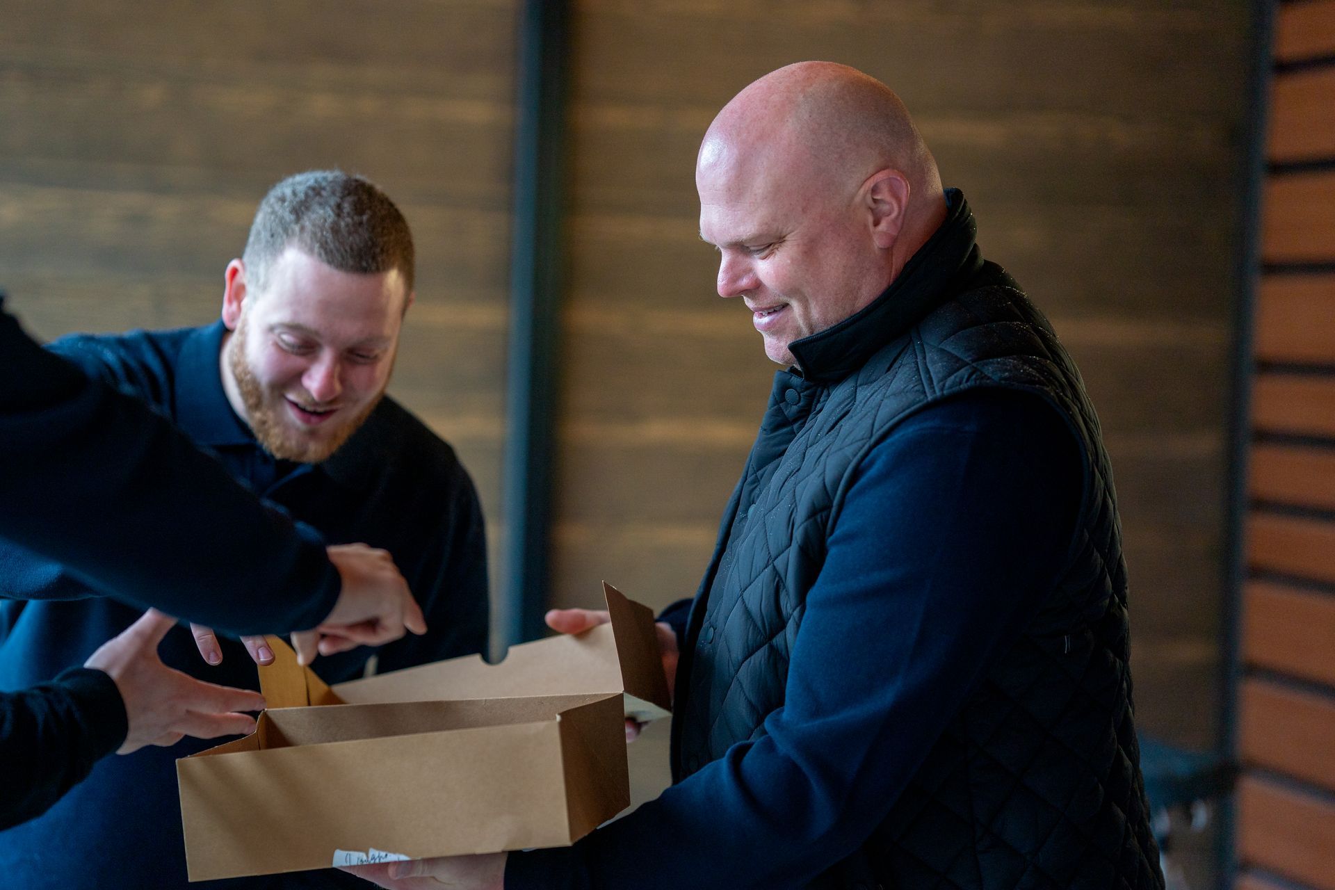 Air conditioning unit next to a house with a wooden deck and stairs, surrounded by greenery.