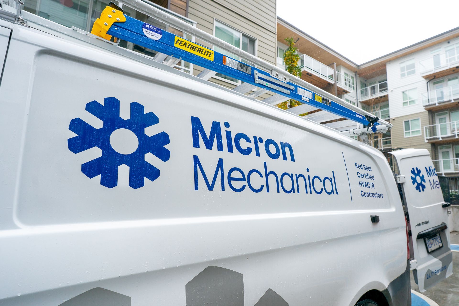 Man in uniform servicing an AC unit outdoors. He's holding a filter, working on the machine.