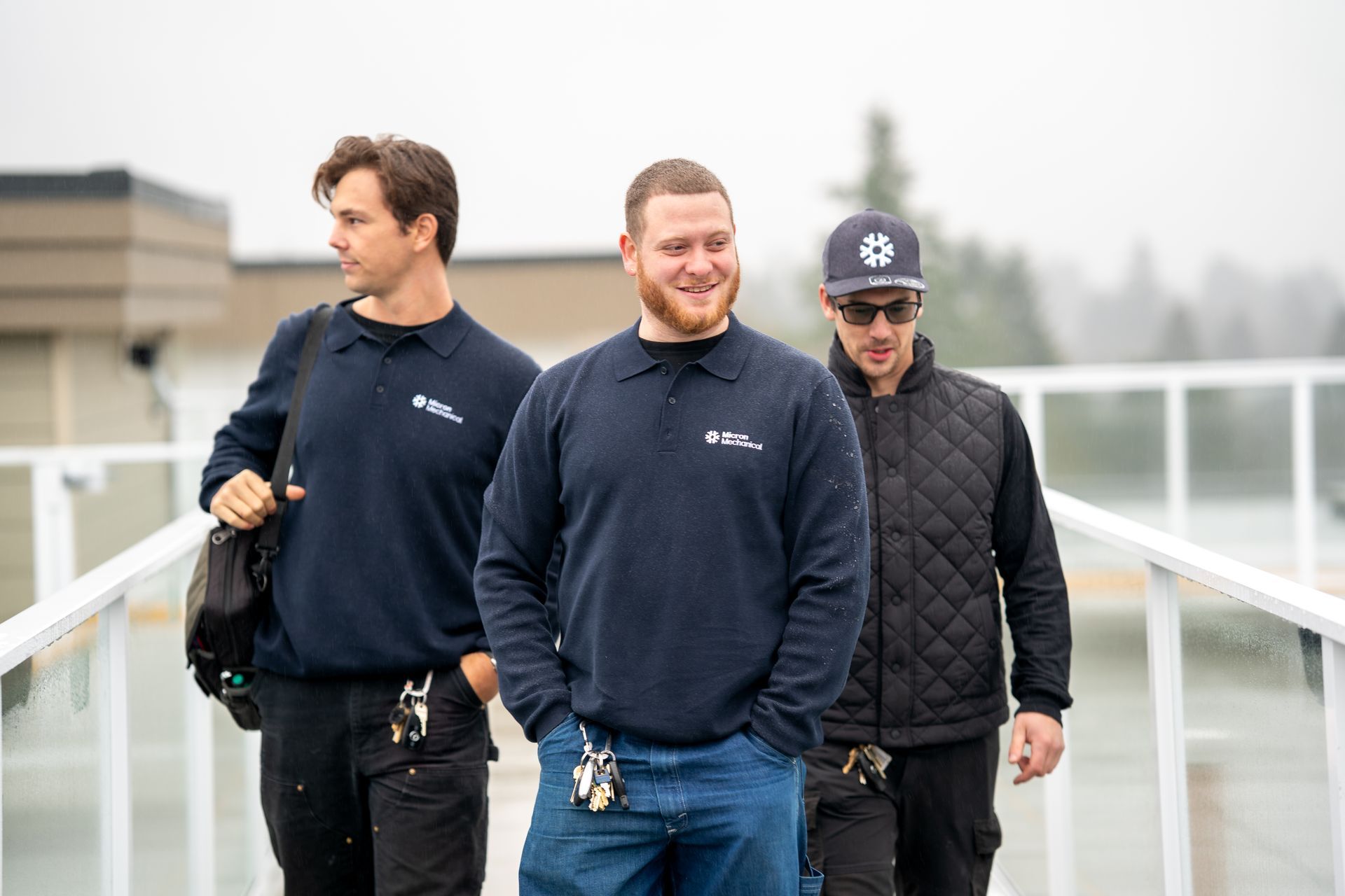 Five people in a cafe sitting at a table with drinks. They are wearing black shirts and smiling.