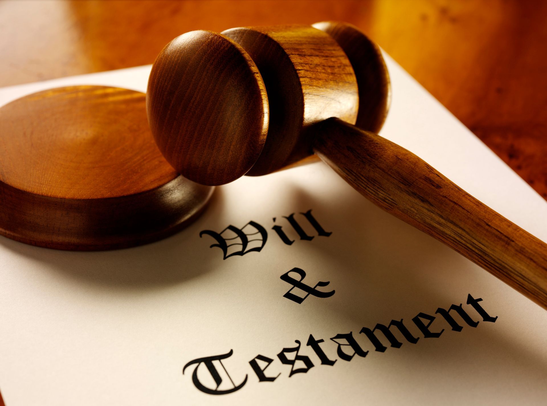 A wooden gavel sits on top of a will and testament