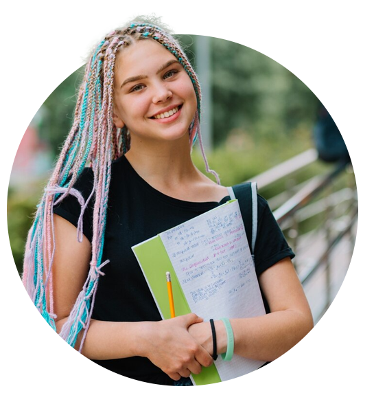 A girl with dreadlocks is smiling while holding a notebook and a pencil.