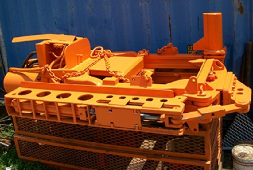 A large orange machine is sitting in front of a blue container