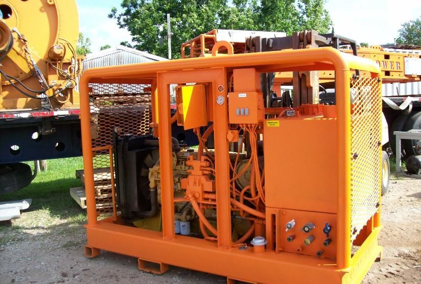 A large orange machine is parked in front of a truck