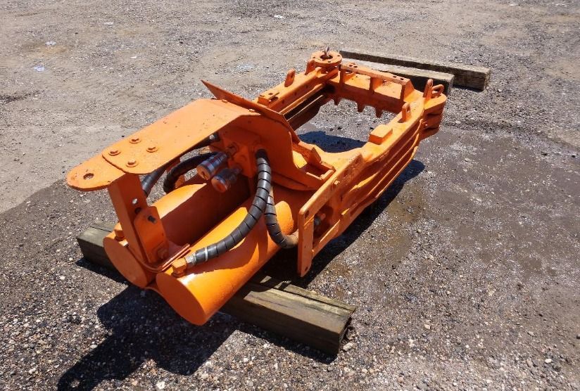 An orange machine is sitting on a wooden pallet on the ground