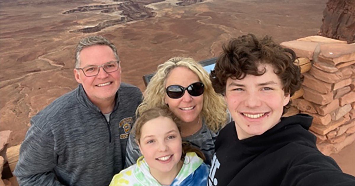 A family is taking a selfie on top of a mountain.