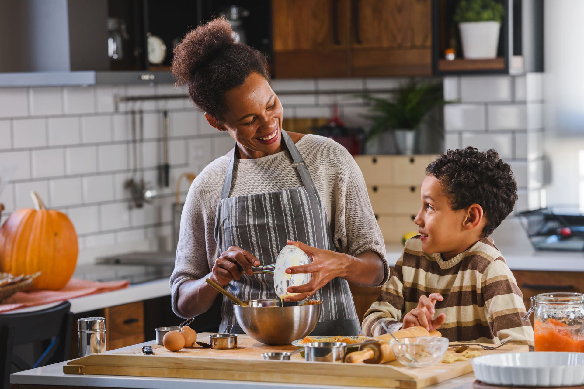 A woman and a boy are preparing food in a kitchen.