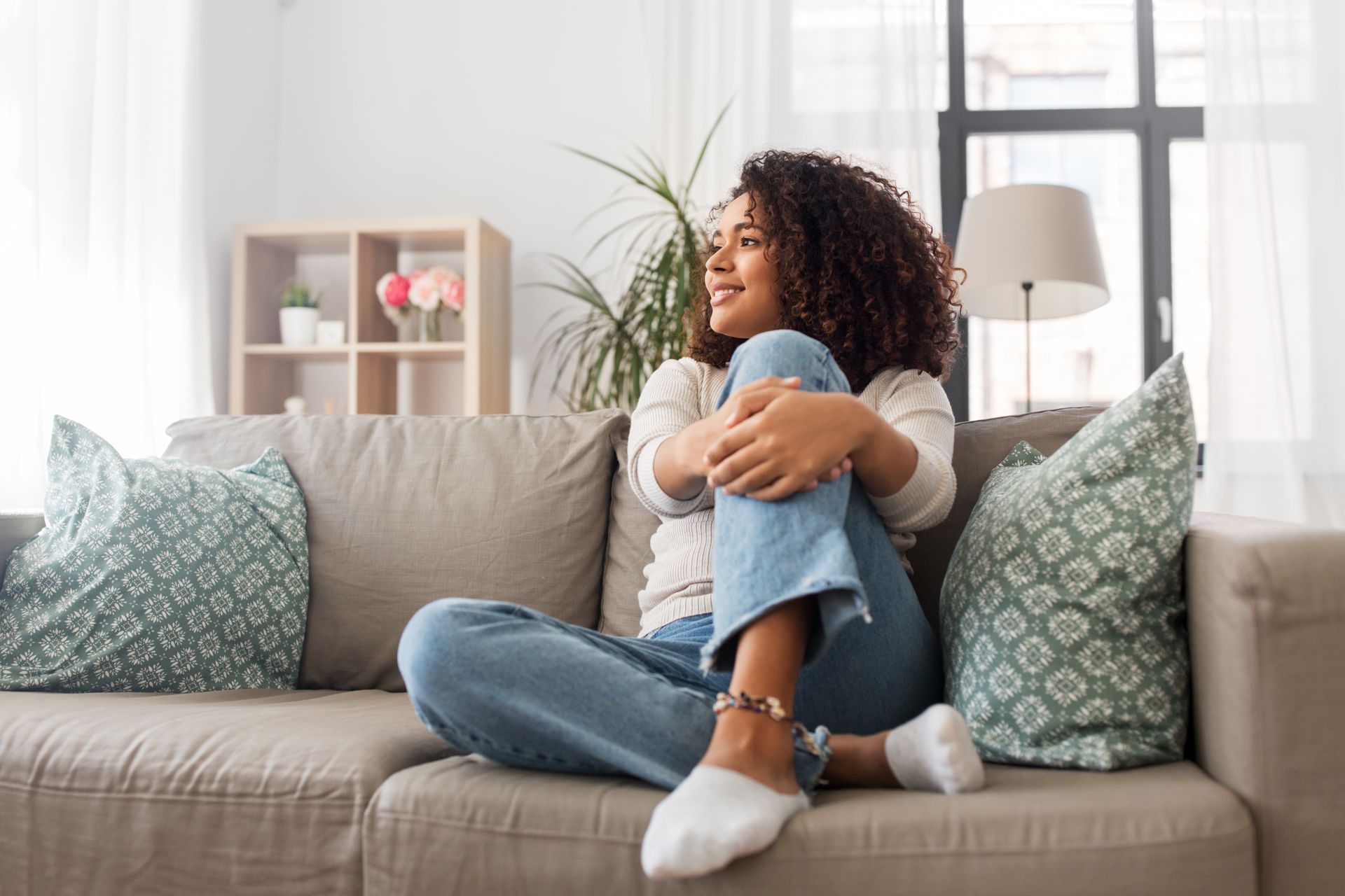 A woman is sitting on a couch with her legs crossed.