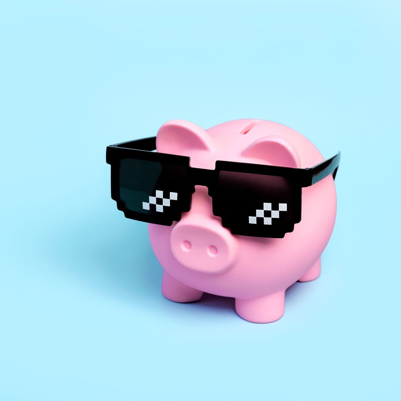 A pink piggy bank wearing sunglasses on a blue background