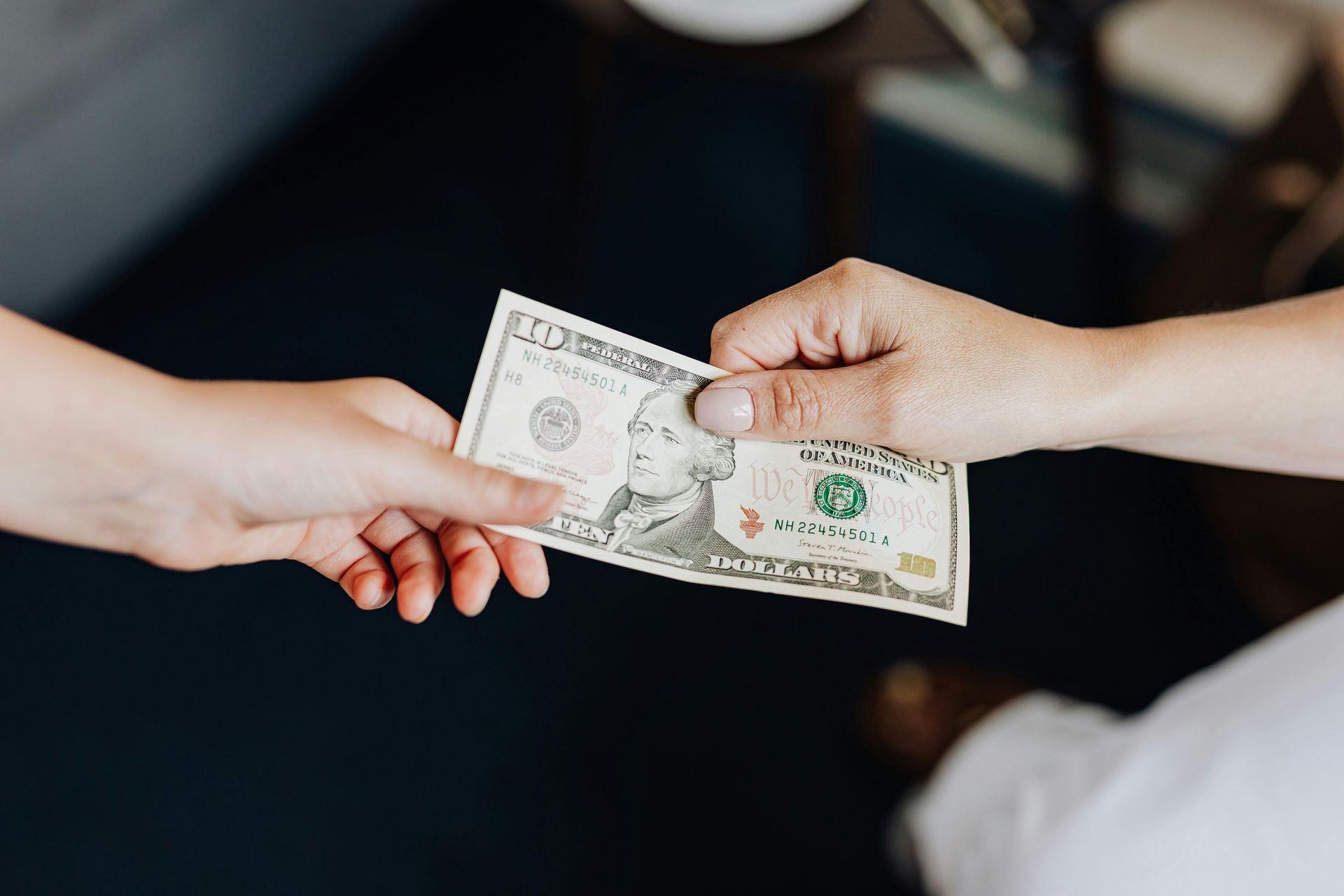 A person is handing another person a dollar bill.