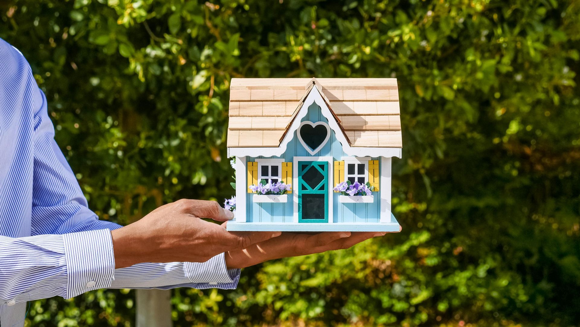 A person is holding a small model house in their hands.