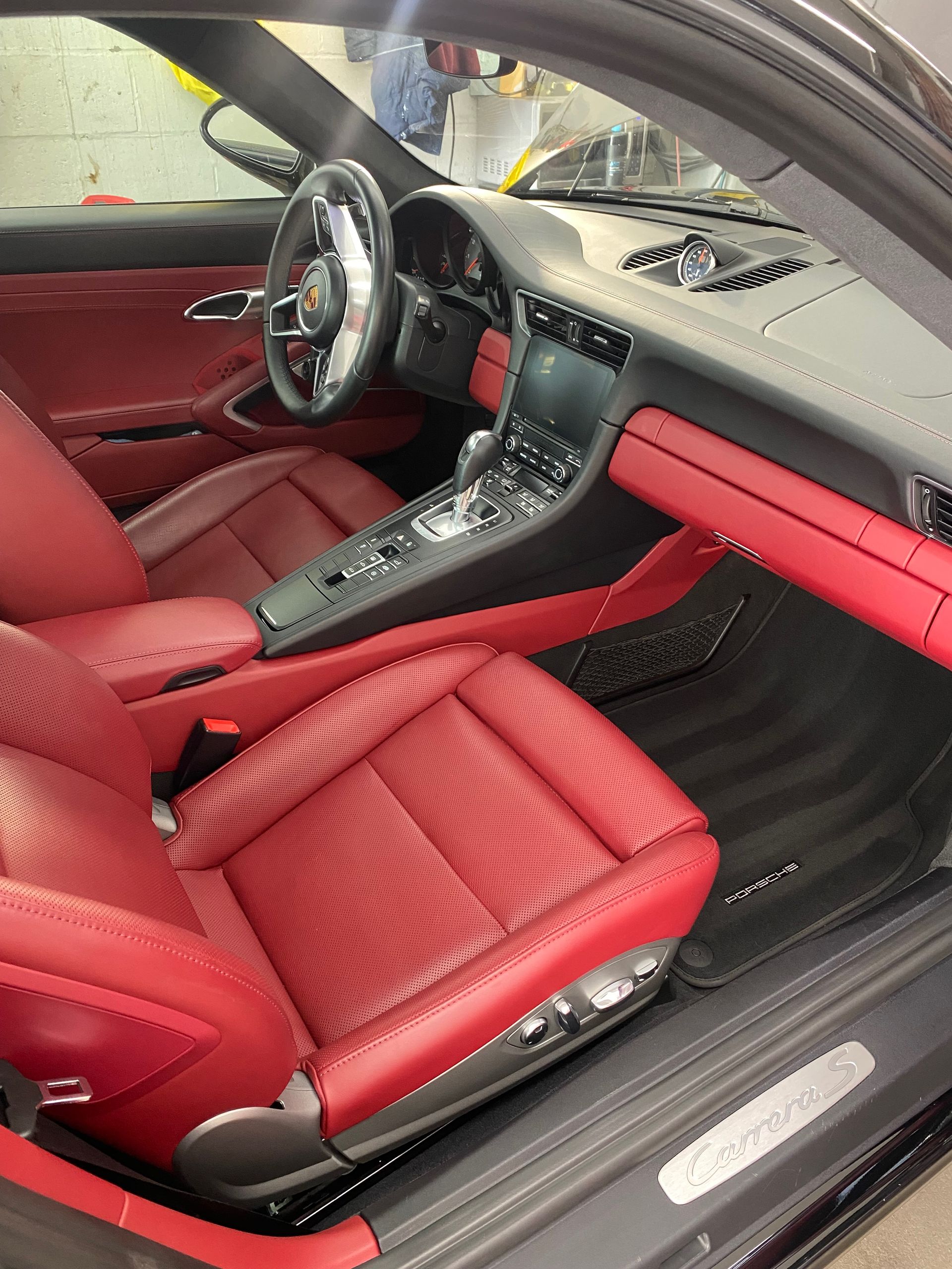 the interior of a black car with red seats and a steering wheel .