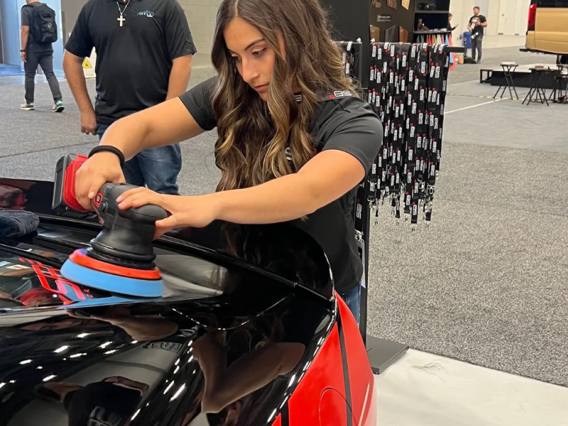 a woman is polishing a car with a machine .