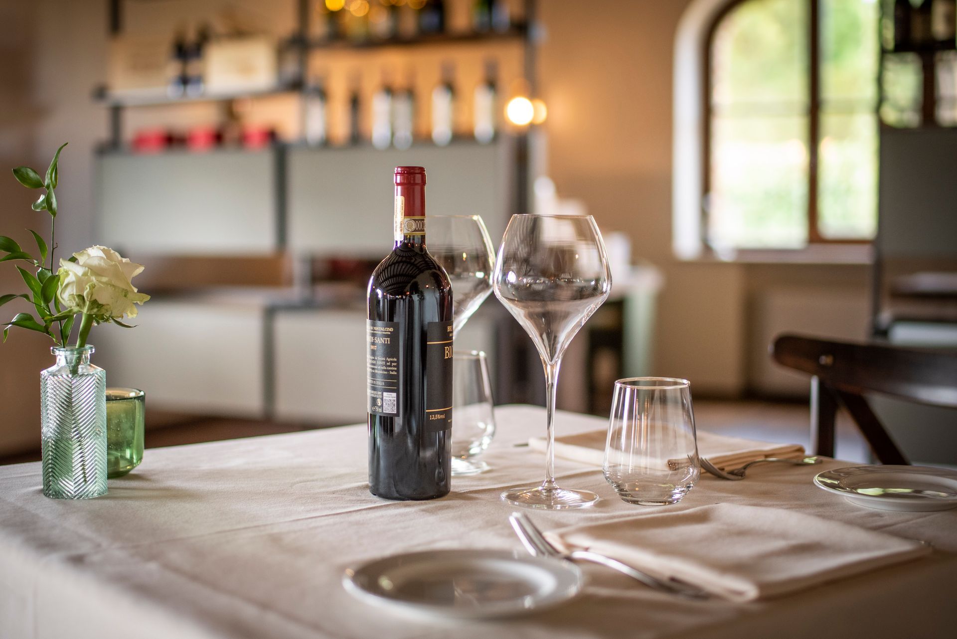 A bottle of wine is sitting on a table next to two wine glasses.