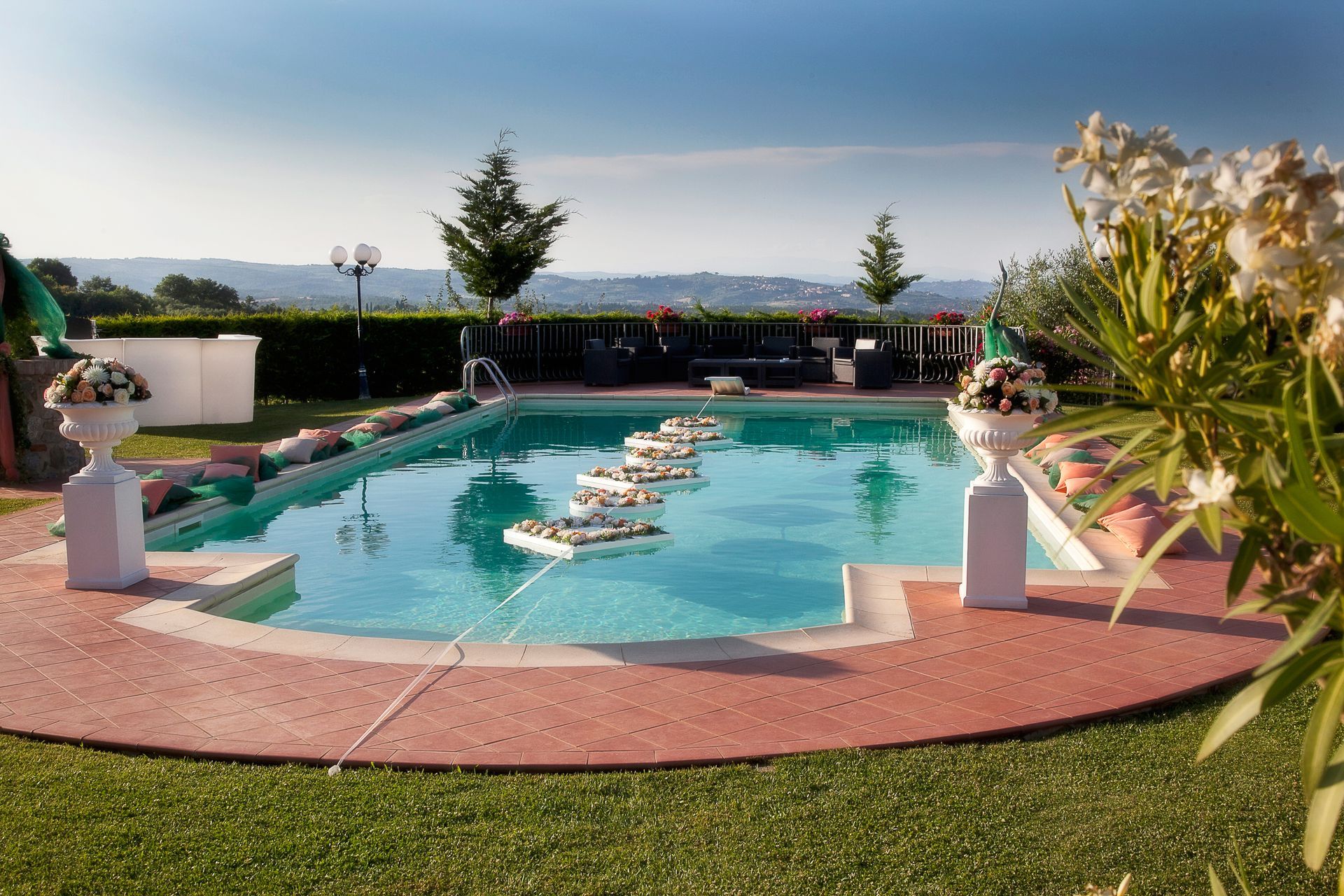 A large swimming pool surrounded by grass and flowers