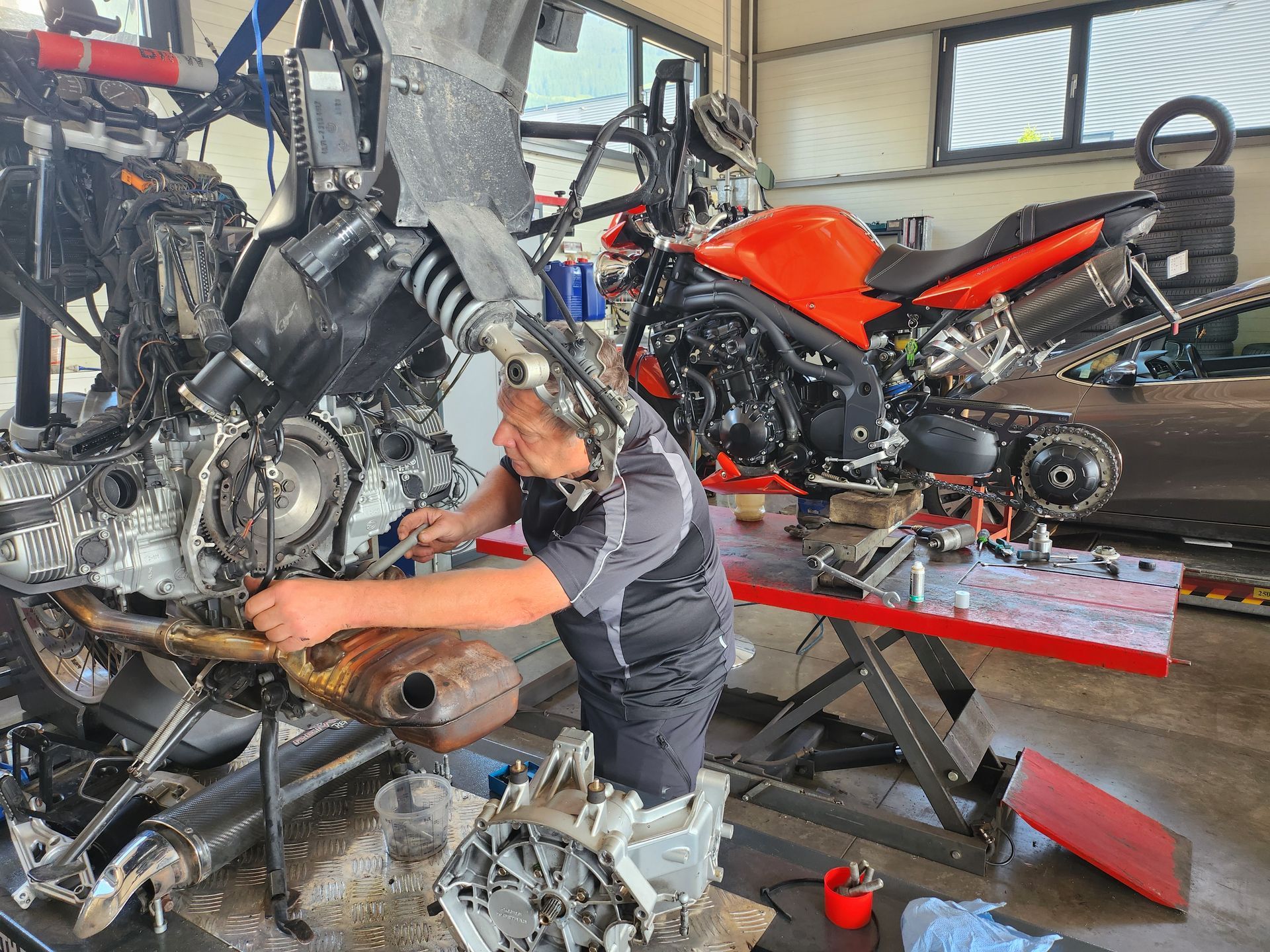 Ein Mann arbeitet in einer Garage arbeitet an einem roten Ducati 999 Motorrad.