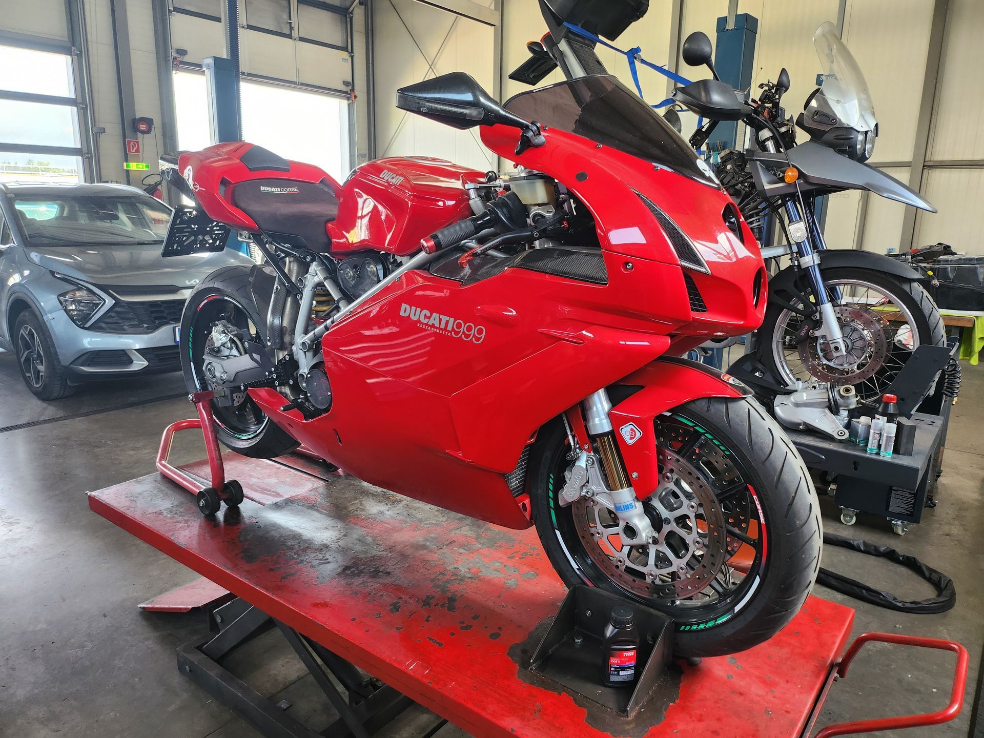 Ein rotes Ducati 999 Motorrad steht auf einer Hebebühne in einer Garage.