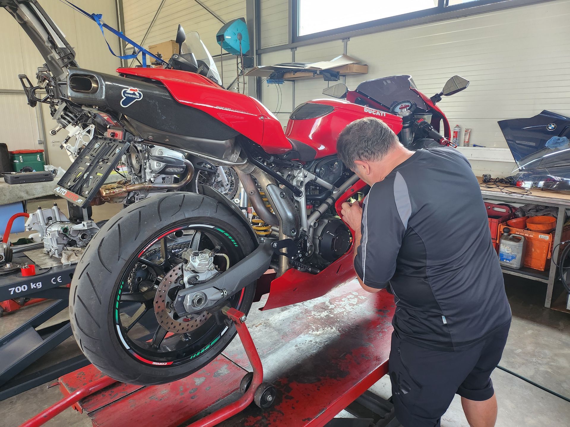 Ein Mann arbeitet in einer Garage arbeitet an einem roten Ducati 999 Motorrad.