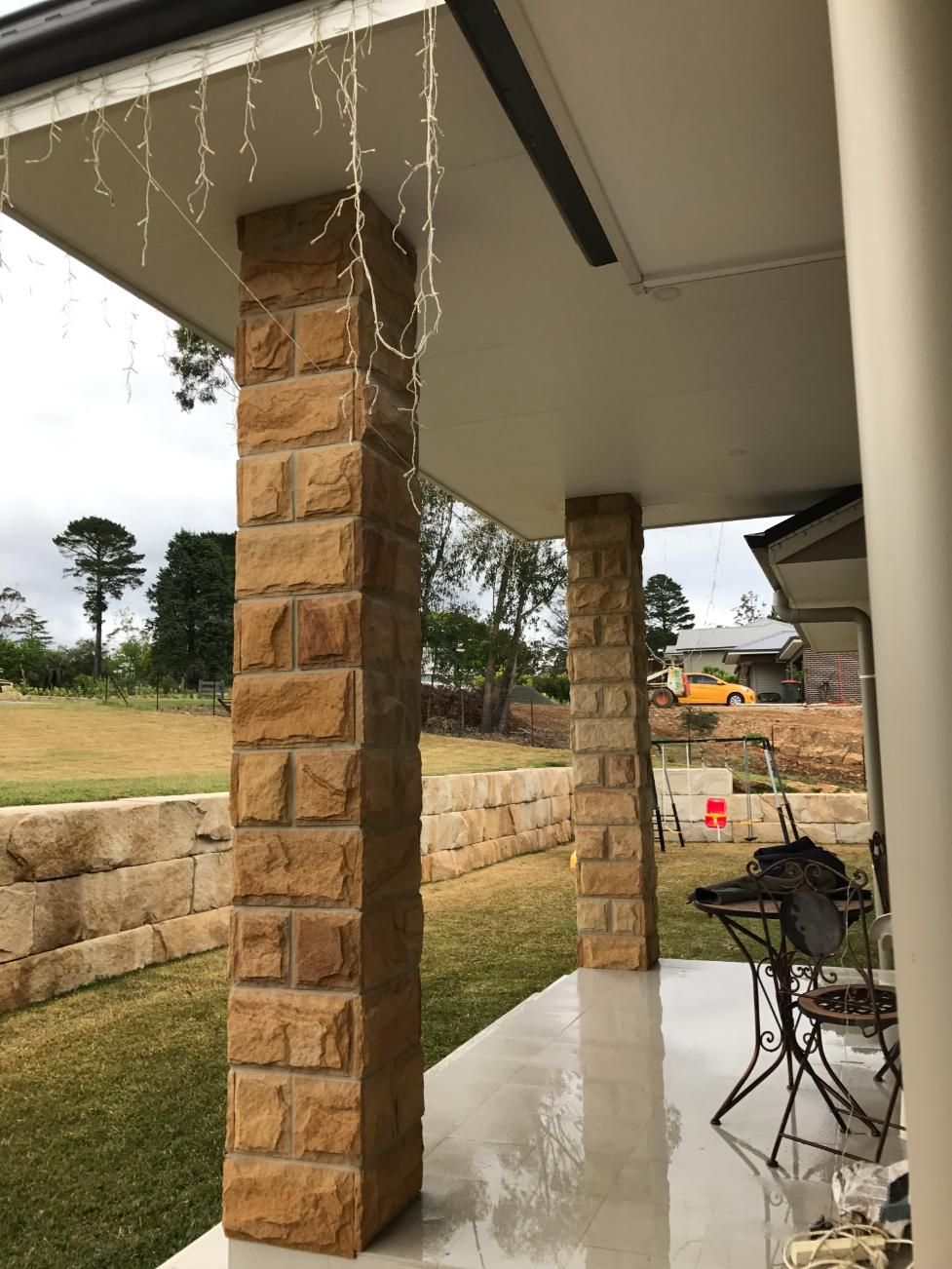 A Porch With Brick Columns And Christmas Lights Hanging From The Ceiling — Lewis Landscapes In Yippin Creek, NSW