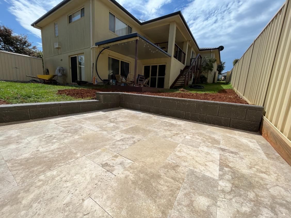 A Large House With A Concrete Patio In Front Of It — Lewis Landscapes In Laurieton