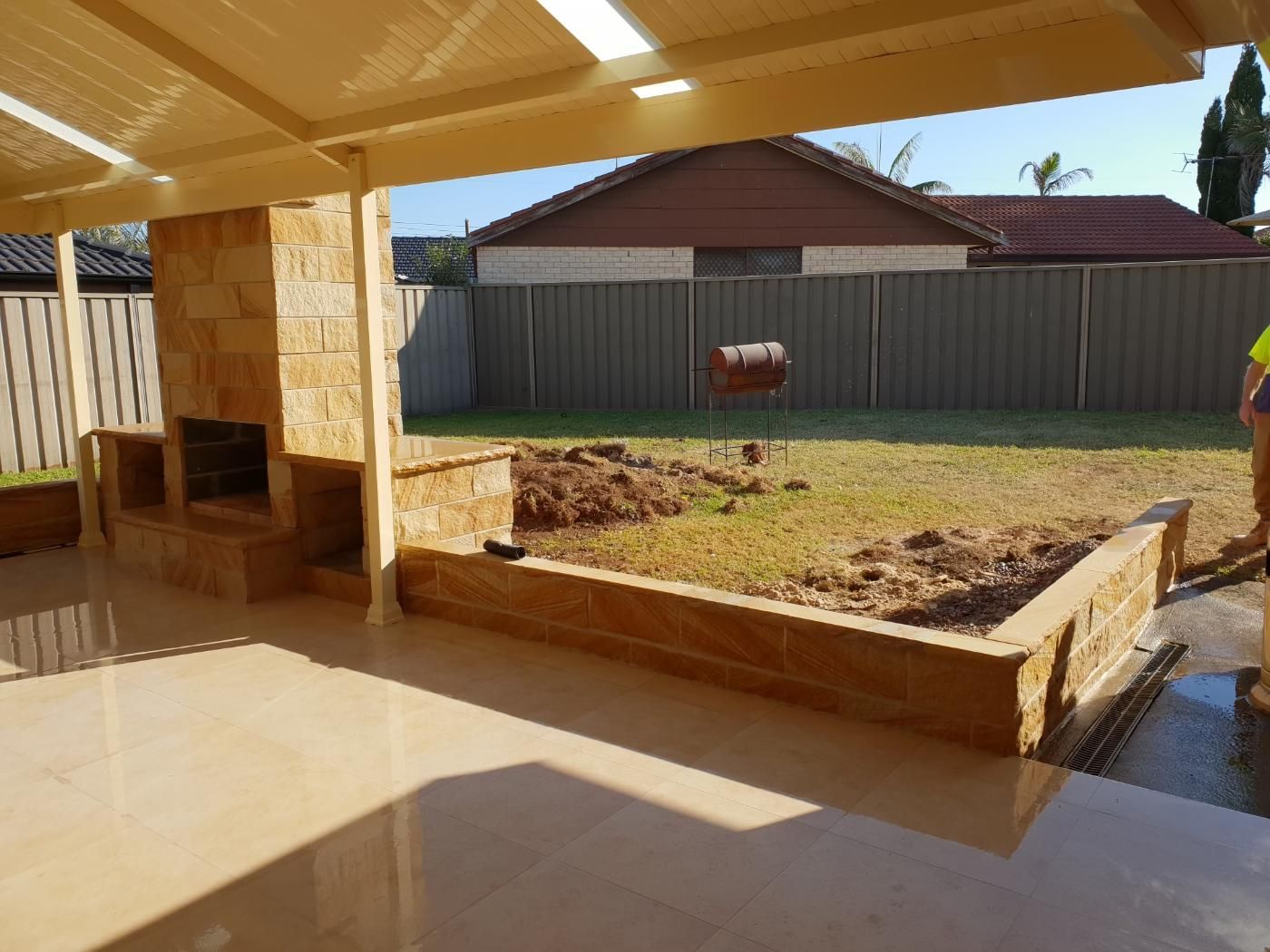 A Man Is Standing In Front Of A Fence In A Backyard — Lewis Landscapes In Yippin Creek, NSW