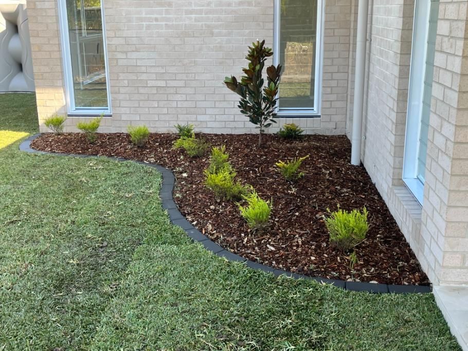 A Brick House With A Lush Green Lawn And A Garden In Front Of It — Lewis Landscapes In Yippin Creek, NSW