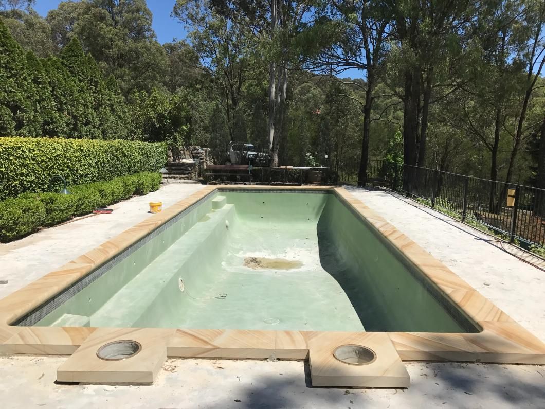 An Empty Swimming Pool Is Surrounded By Trees And Bushes — Lewis Landscapes In Laurieton