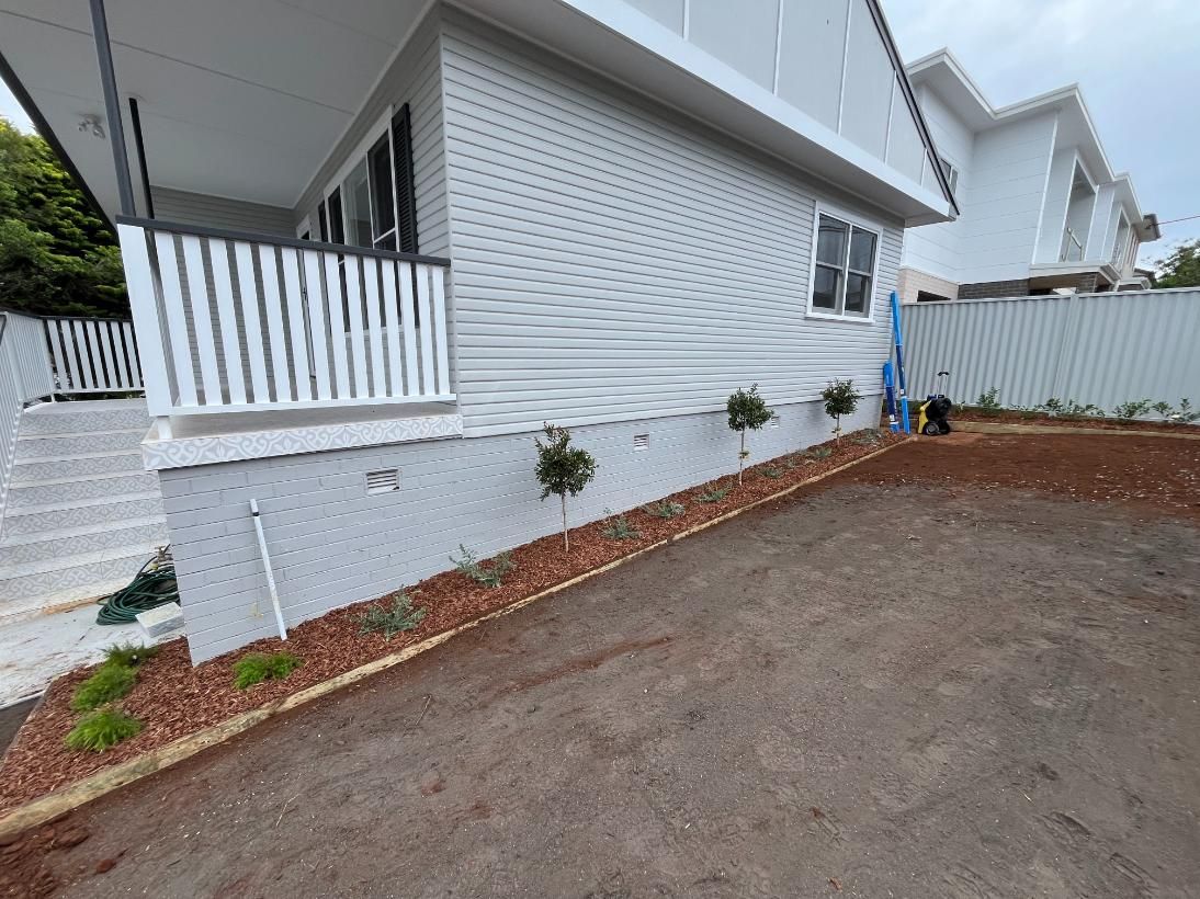 A White House With A Porch And A Fence In Front Of It — Lewis Landscapes In Port Macquarie, NSW
