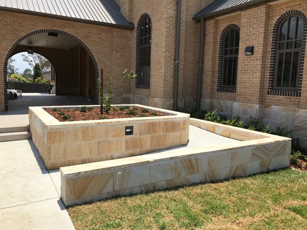 A Brick Building With A Planter In Front Of It — Lewis Landscapes In Yippin Creek, NSW