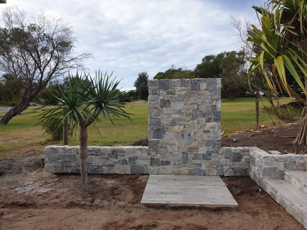 A Stone Wall With A Palm Tree In The Background — Lewis Landscapes In Yippin Creek, NSW