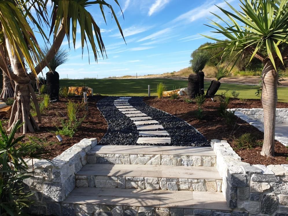 A Stone Walkway Leading To A Golf Course Surrounded By Palm Trees — Lewis Landscapes In Yippin Creek, NSW