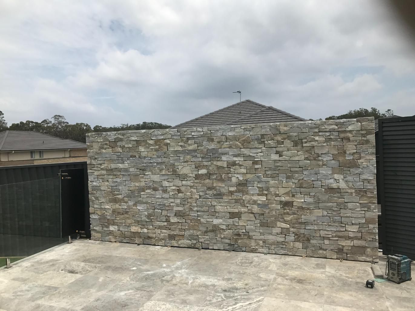 A Large Stone Wall Is Being Built In Front Of A House — Lewis Landscapes In Yippin Creek, NSW