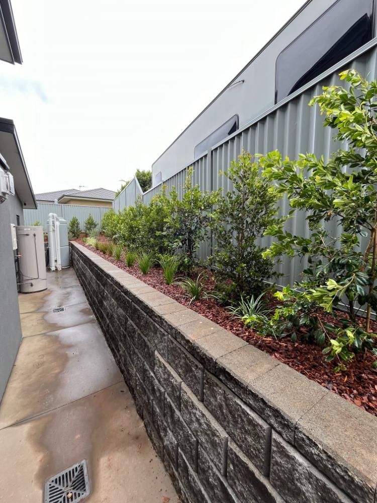A Brick Wall Along A Sidewalk Next To A Fence — Lewis Landscapes In Yippin Creek, NSW