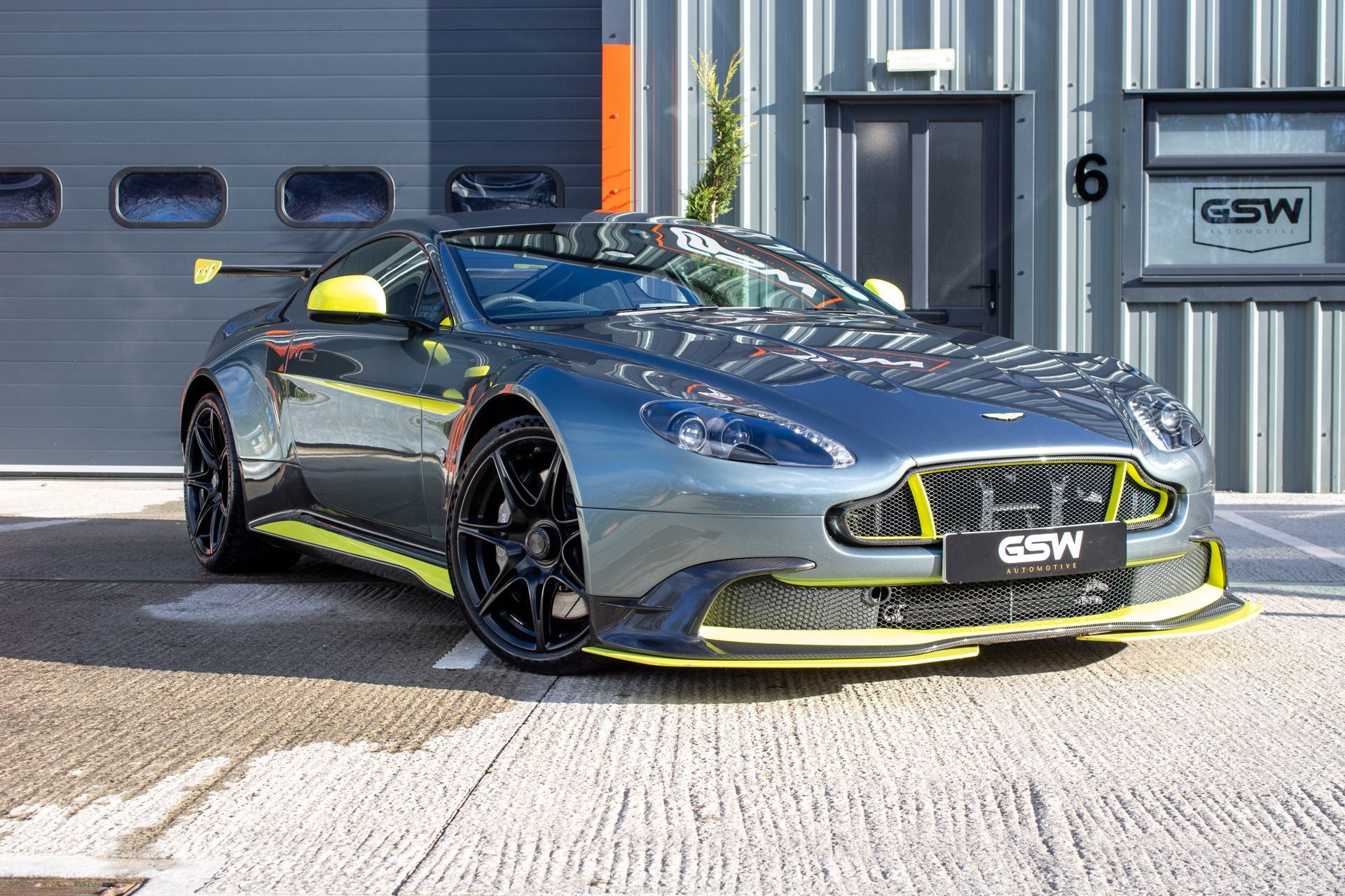 A gray and yellow sports car is parked in front of a building.