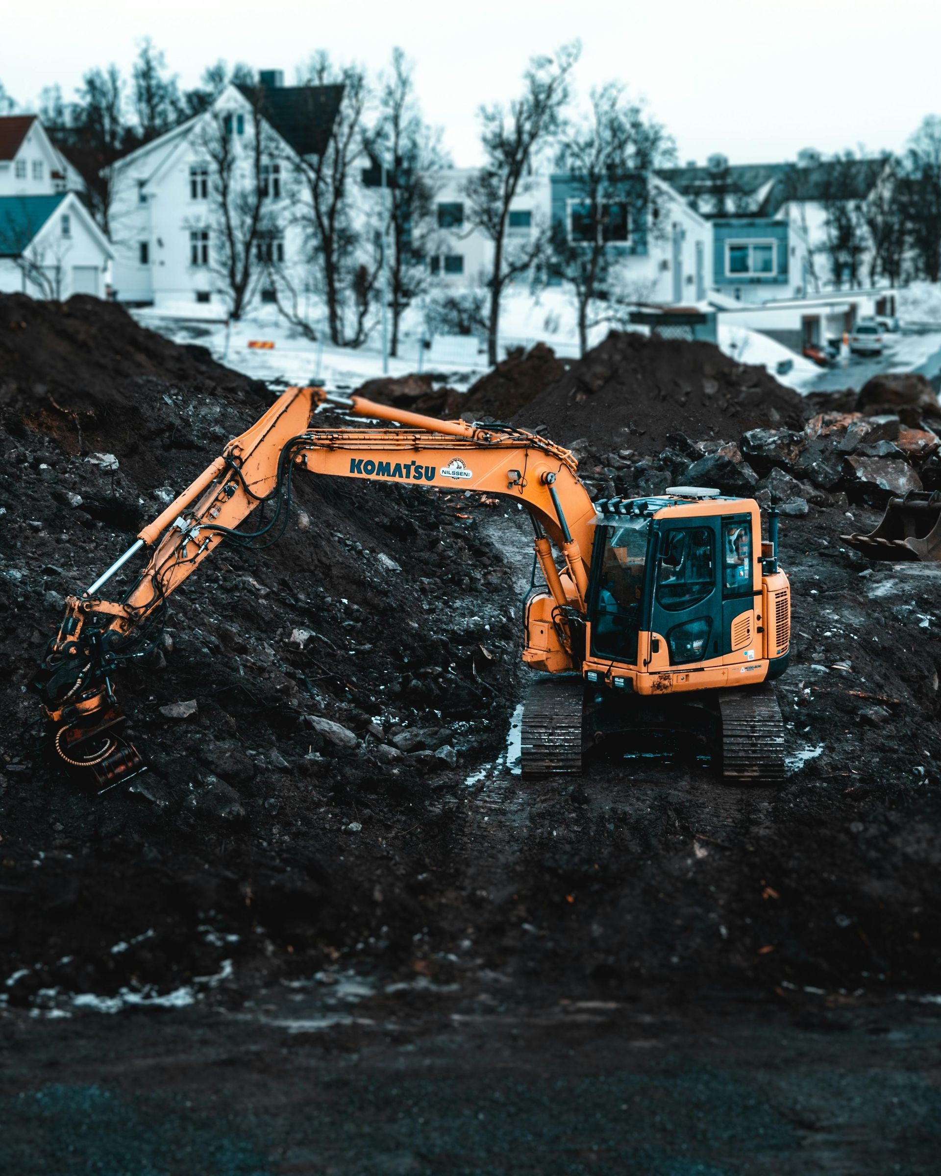 A yellow excavator is digging in a pile of dirt.