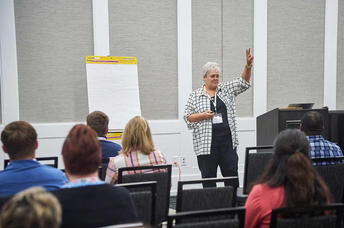 A woman is giving a presentation to a group of people sitting in chairs.