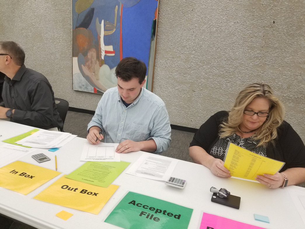 A man and a woman are sitting at a table with a sign that says accepted file