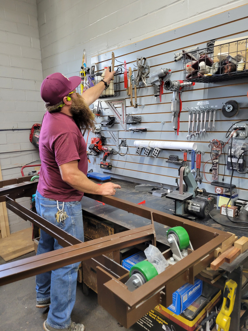 A man is working on a piece of metal in a workshop.