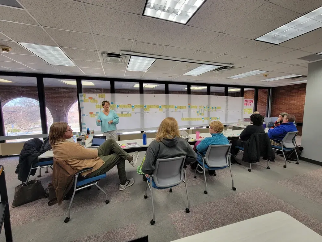 A woman is giving a presentation to a group of people in a classroom.