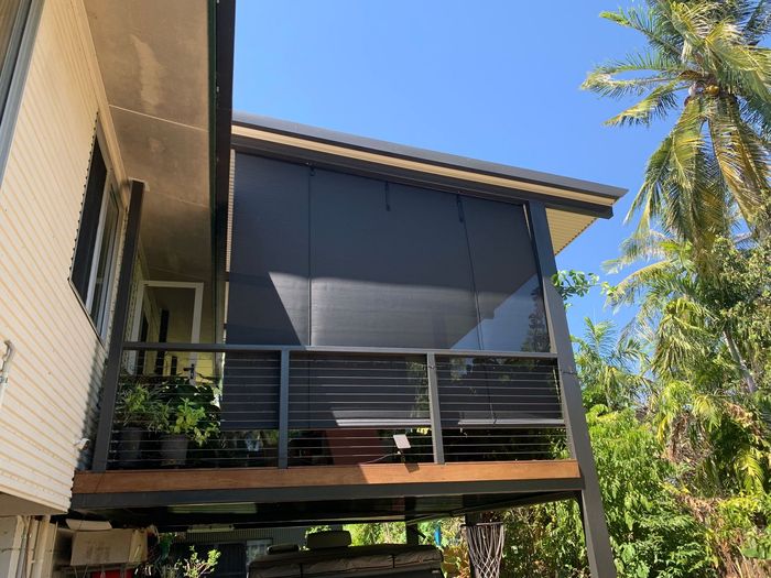 Modern house exterior with screened balcony, dark shutters, and palm trees against a blue sky — Blinds in Darwin NT