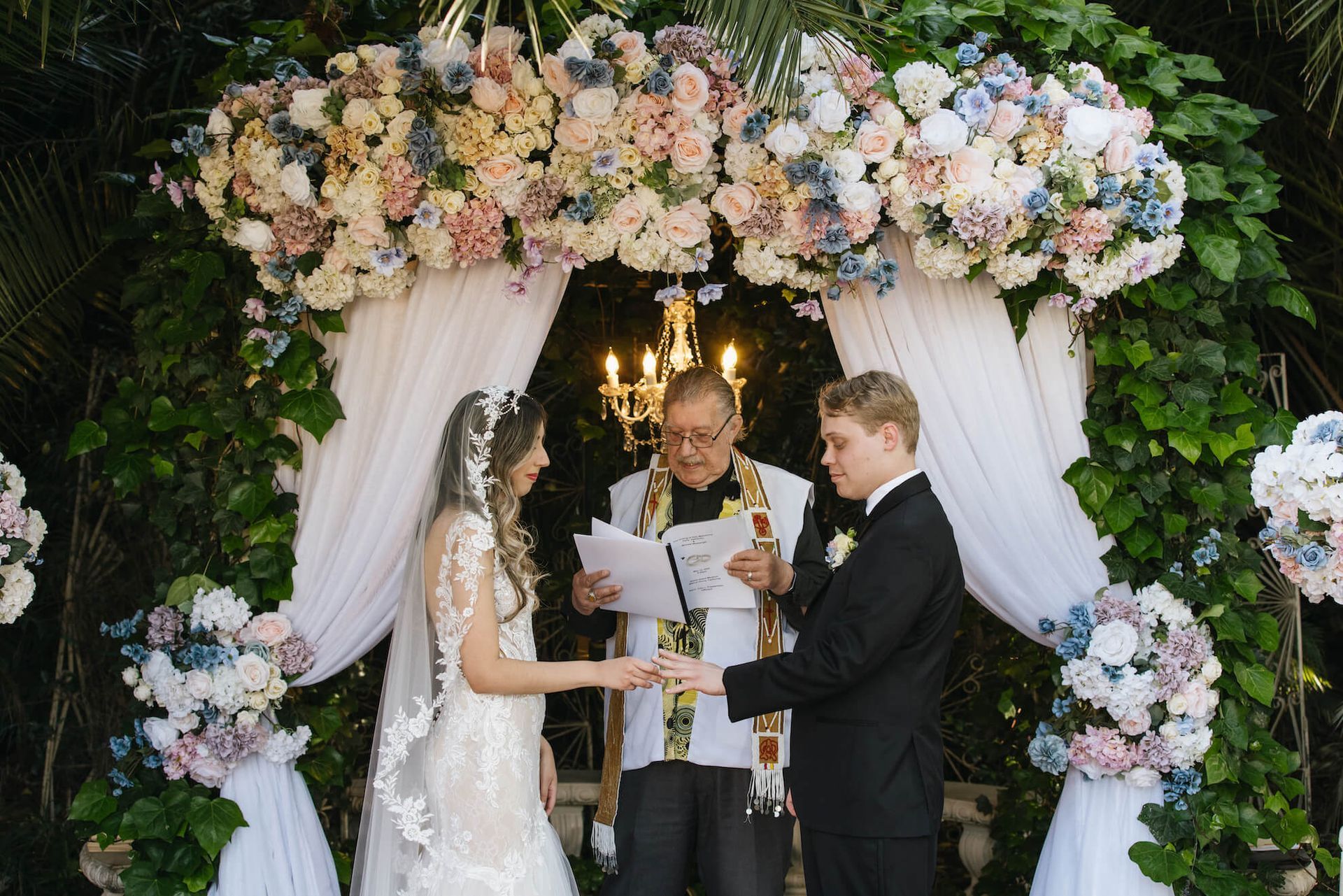 a bride and groom are getting married under a floral arch