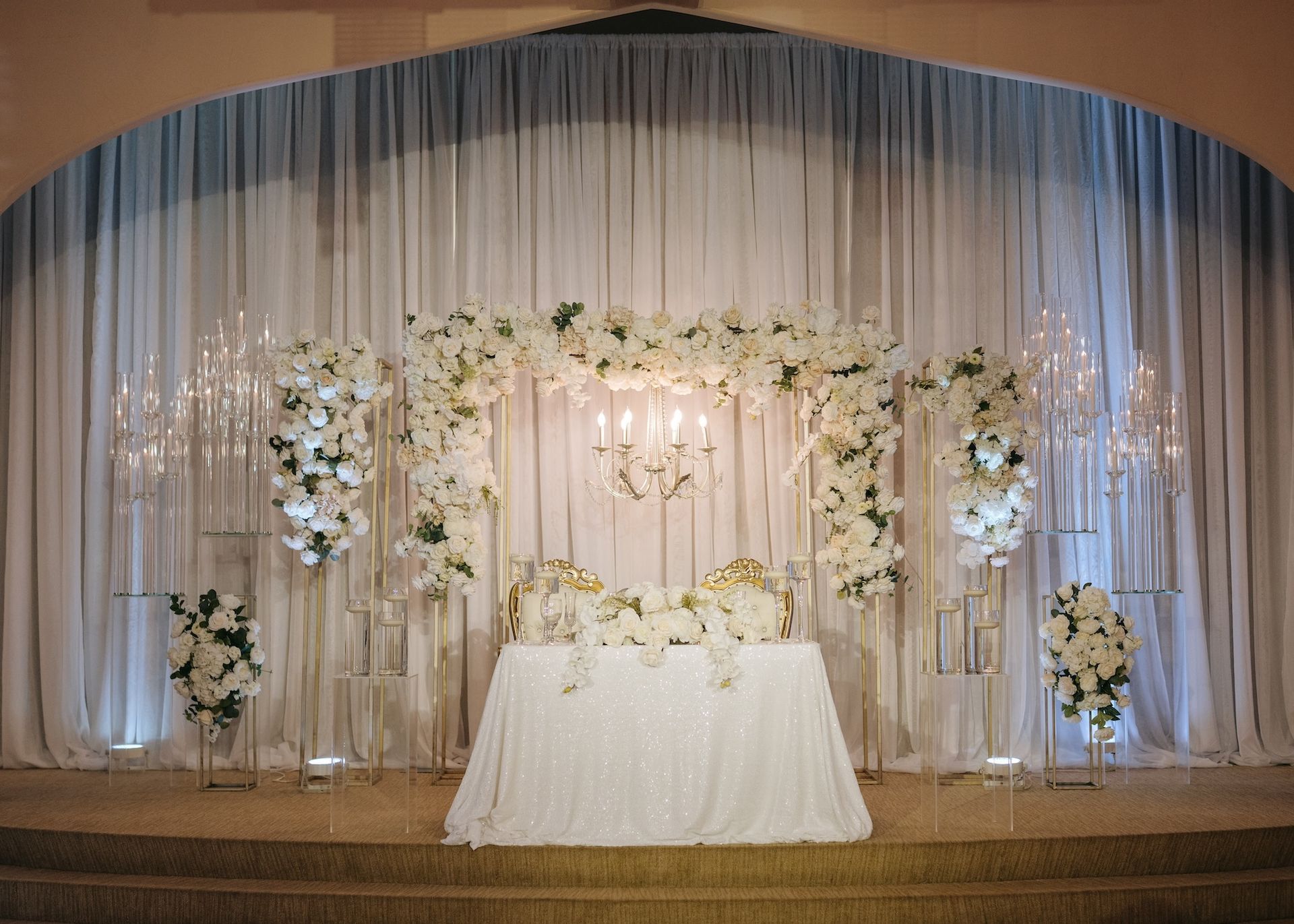 The bride and groom 's table is decorated with white flowers and candles.