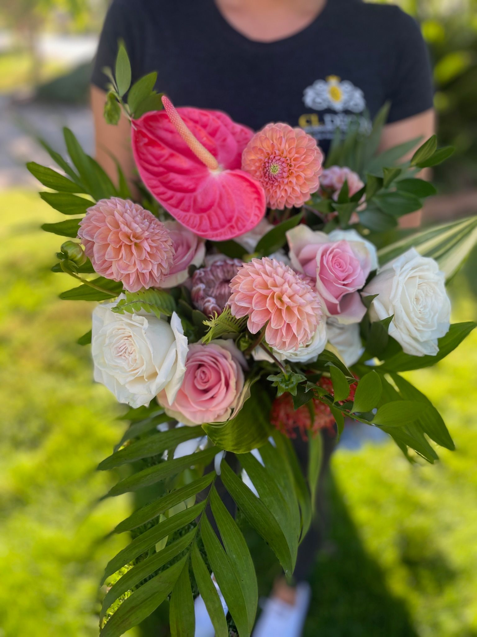 Person holding a bouquet of pink and white flowers and greenery.