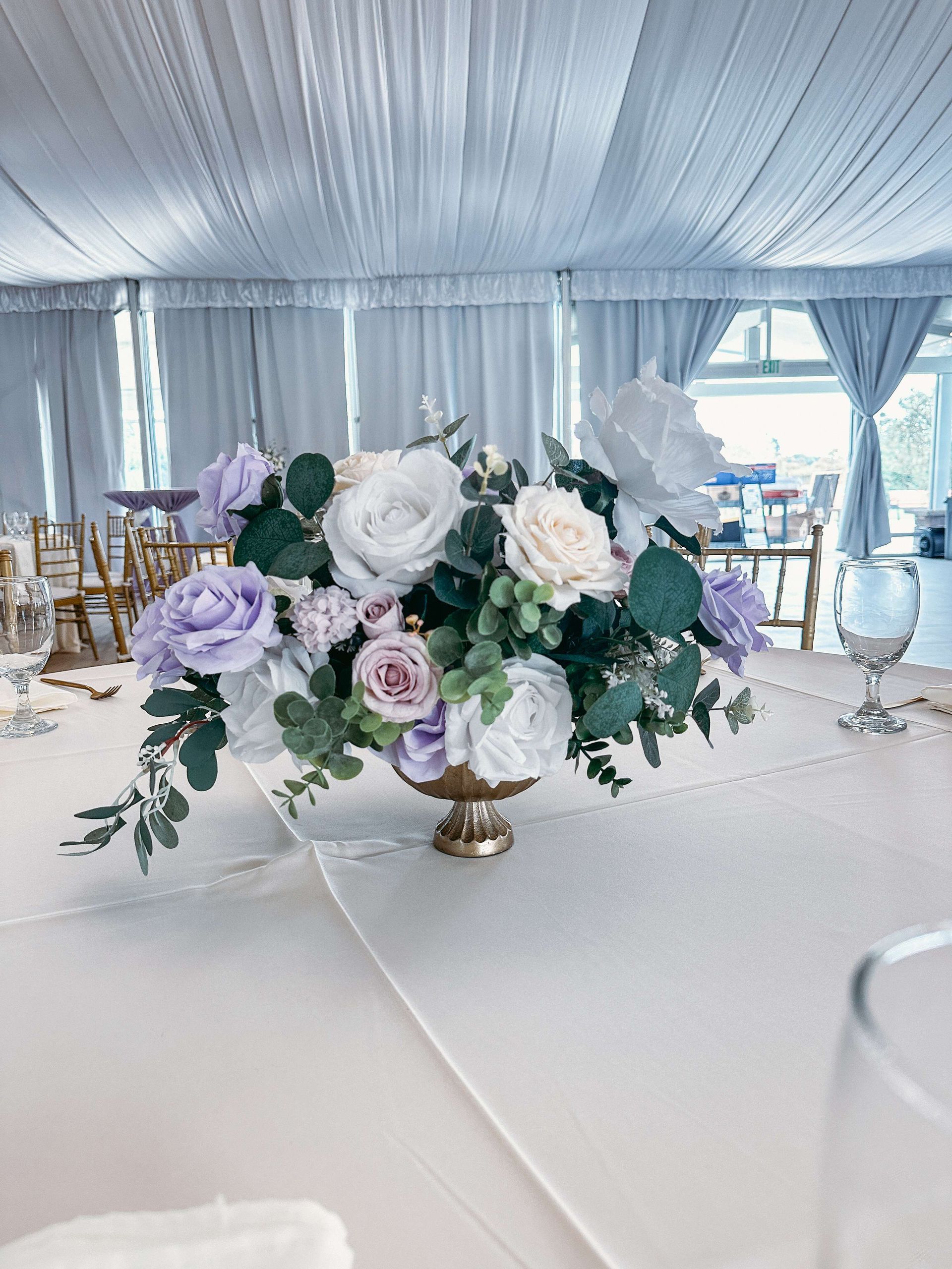 Floral centerpiece with lavender and white roses on a table at an event.