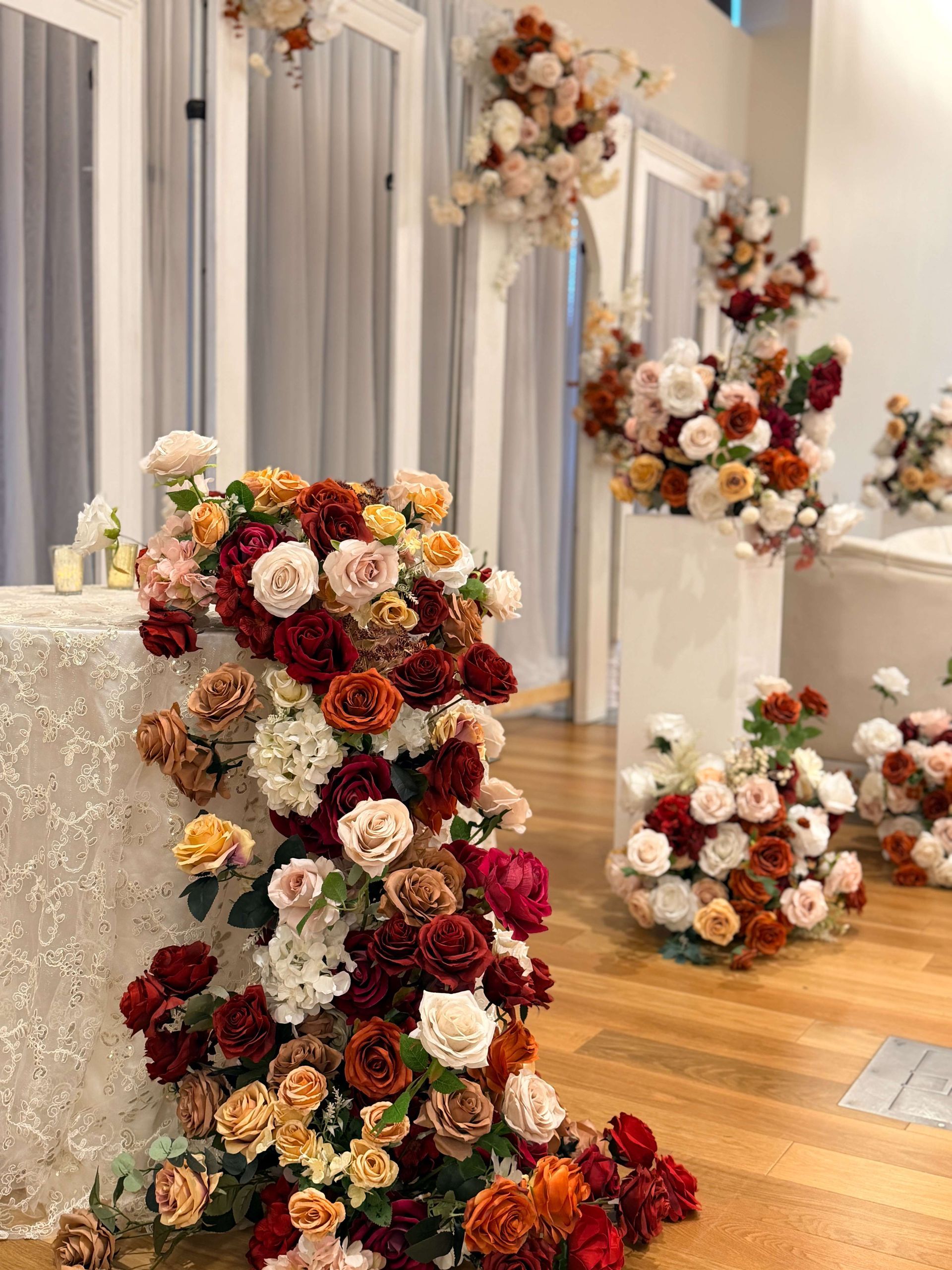 Floral arrangements in shades of red, peach, and cream decorate a wedding venue.