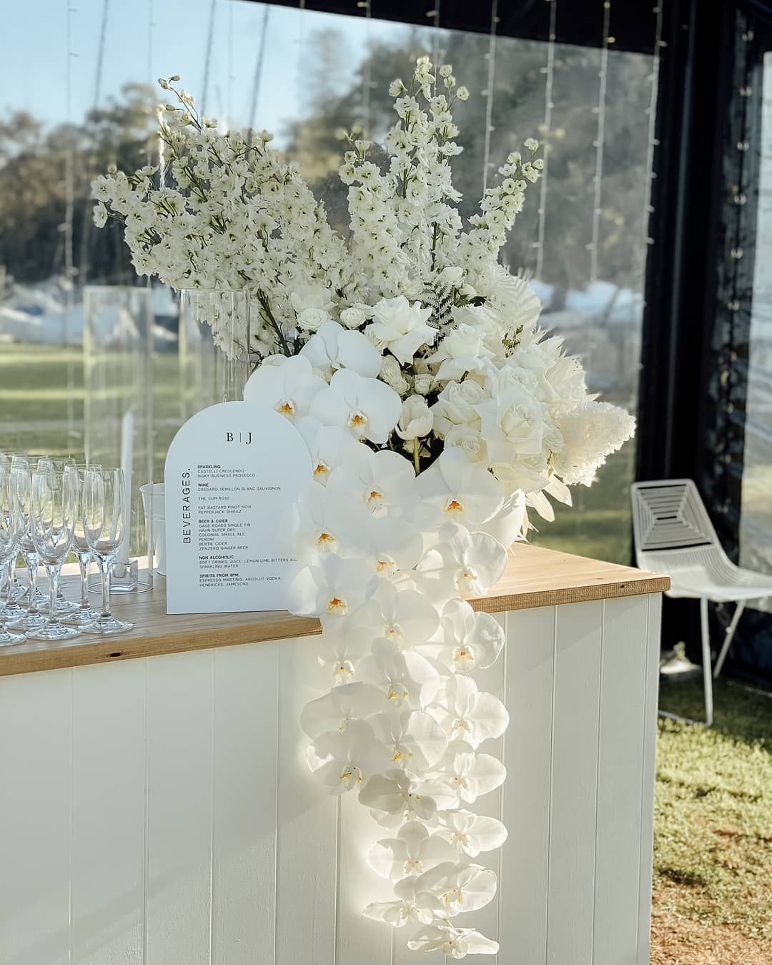 White floral arrangement cascading down a white bar, with a menu sign.