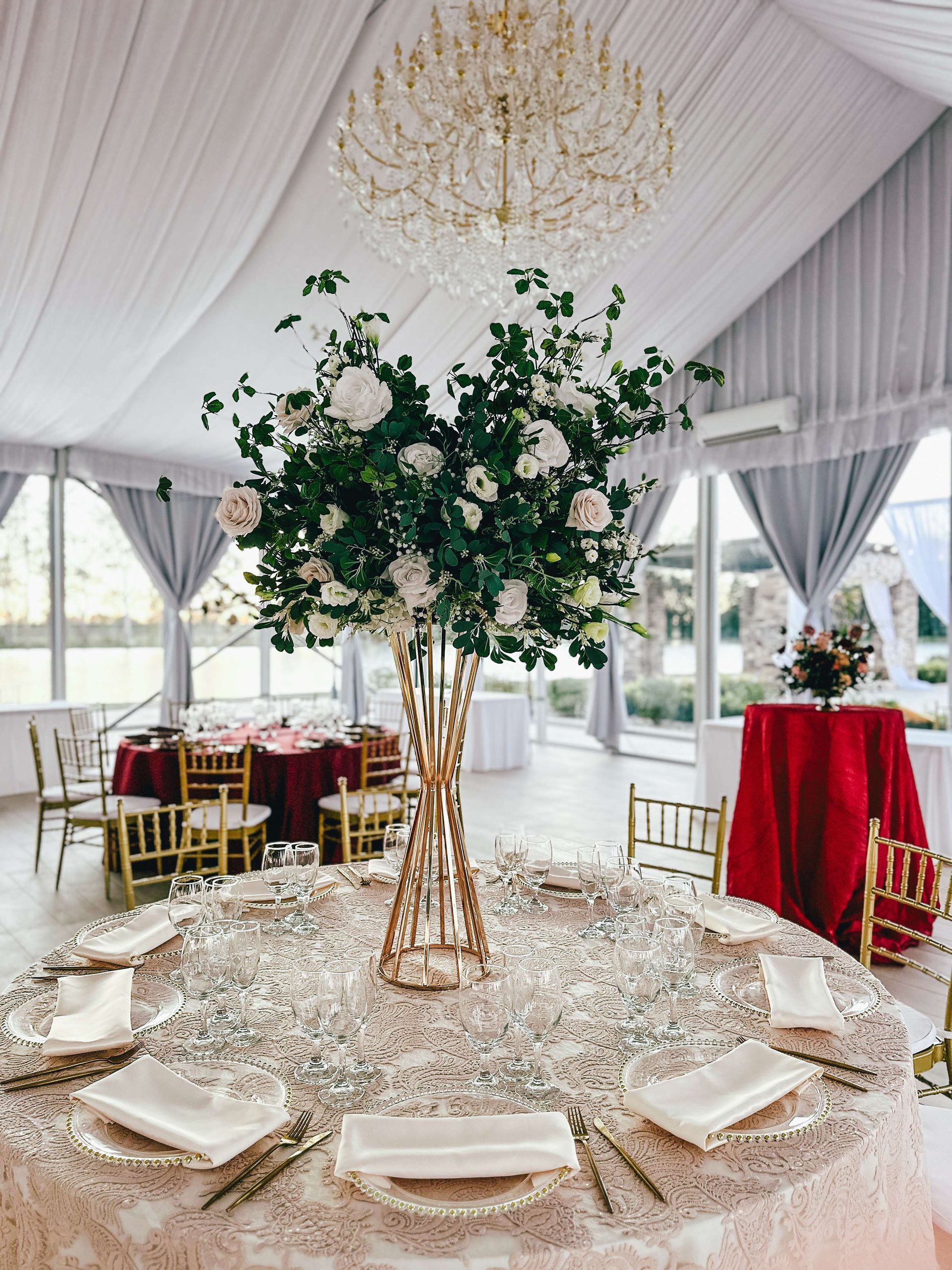 Elegant reception table with floral centerpiece, sparkling tablecloth, gold accents, and chandelier.
