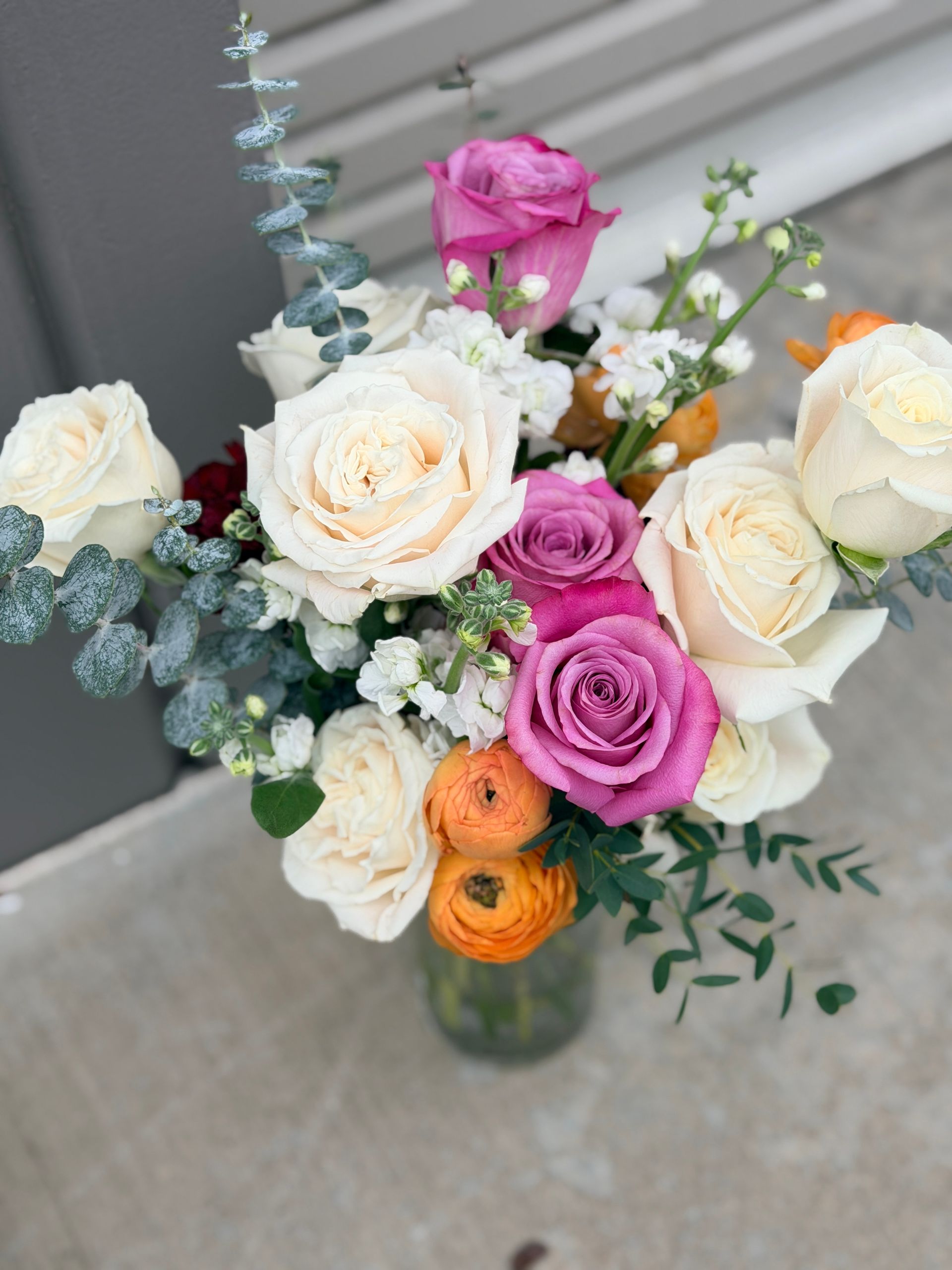 Bouquet of white, pink, and orange flowers in a clear vase.
