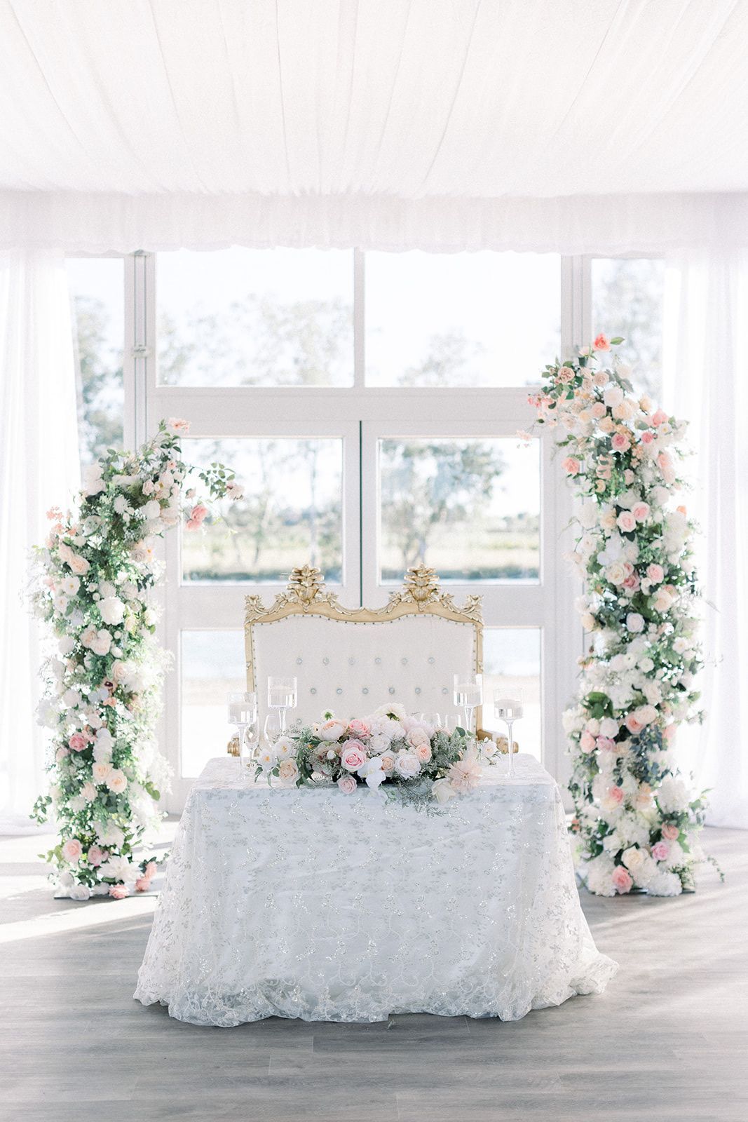 a table with a chair and flowers on it in front of a window and backdrop