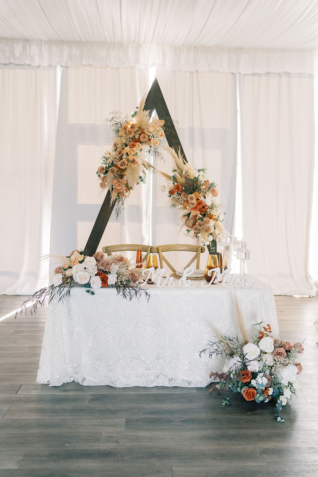a table with a triangle shaped backdrop and flowers on it and backdrop
