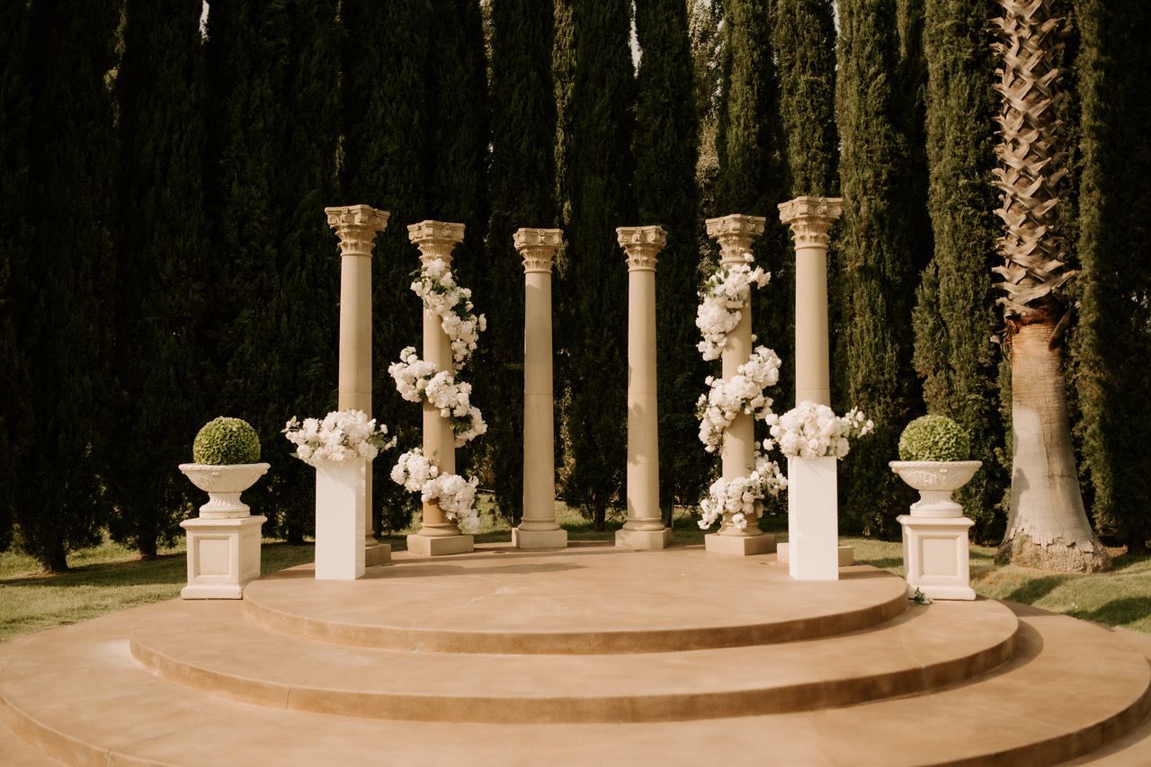 a circular podium with columns and vases surrounded by trees and backdrop